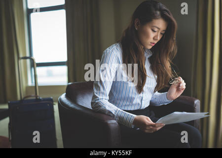 Businesswoman reading document while sitting on arm chair Stock Photo