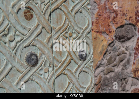 Isolated, close-up of light green carved wooden panels, next to a stone wall, in Mexico Stock Photo