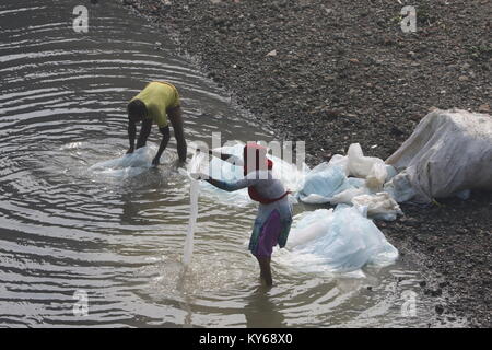 Workers wash plastic chemical bag in the polluted Buriganga River in dhaka. Stock Photo