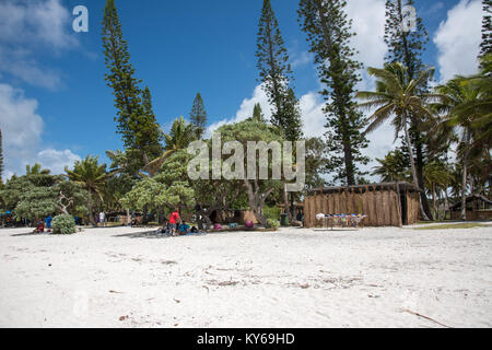 TADINE,MARE,NEW CALEDONIA-DECEMBER 3,2016: Tourists, rustic architecture and tropical flora at Yejele Beach in Mare, New Caledonia Stock Photo