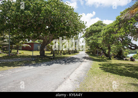 TADINE,MARE,NEW CALEDONIA-DECEMBER 3,2016: Greenery, roadway and tourists resting on grassy shoreline at Yejele Beach in Mare, New Caledonia Stock Photo