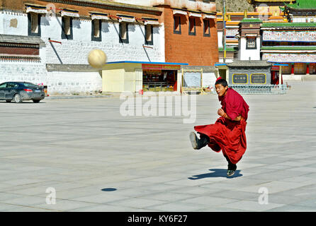 A Tibetan monk playing football in the courtyard of Labrang monastery in Xiahe, Gansu Province, China Stock Photo