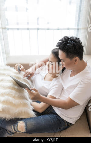 Young Couples using tablet to shopping with credit card in living room of contemporary house for modern lifestyle and e-commerce concept Stock Photo