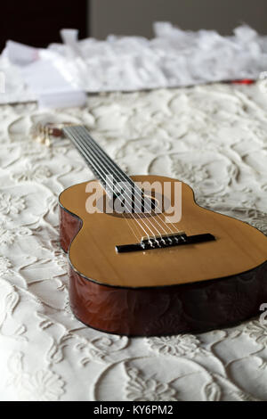 Spanish guitar lying on the bed Stock Photo