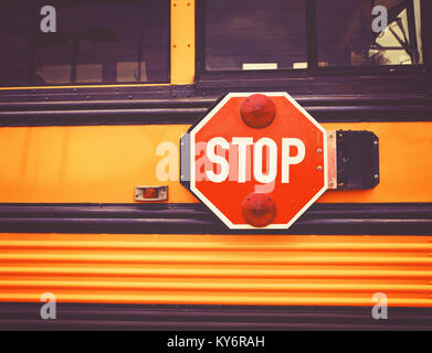 wide angle front view of a bright yellow orange school bus and the big red stop sign Stock Photo