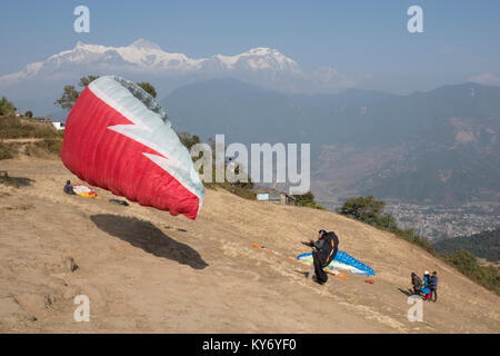 Paragliders preparing for takeoff on hillside launching spot at Sarankot, Nepal Stock Photo