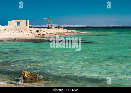 The ruined house with old metal structures on the sea shore. Red Sea in Sharm El Sheikh, Egypt. Stock Photo