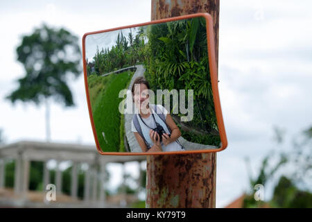 Travelling in Bali rice terrace. Caucasian woman smile in road mirror Stock Photo