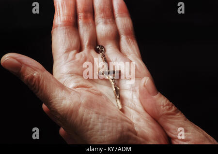Close-up of a female hand holding rosary beads and a crucifix - John Gollop Stock Photo