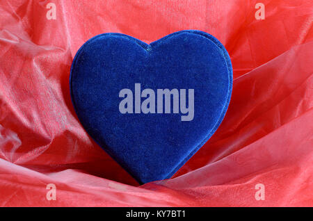 Blue velvet heart on red tulle fabric Stock Photo