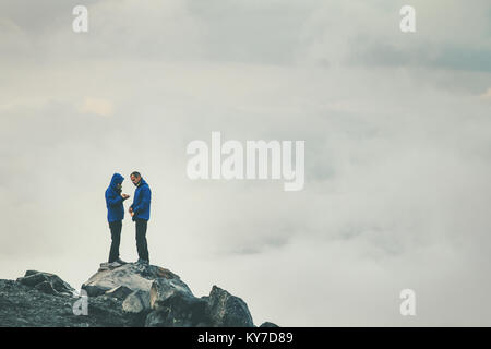 Couple Travelers in love standing on cliff together enjoying cloudy foggy mountains landscape Travel Lifestyle freedom concept adventure vacations out Stock Photo