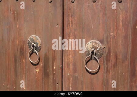 Ancient gate of brown wood figure with unusual handles Stock Photo
