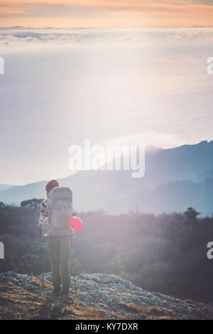 Woman Traveler with backpack hiking on cliff Travel Lifestyle concept adventure active vacations outdoor sunset aerial view from mountain summit on ba Stock Photo