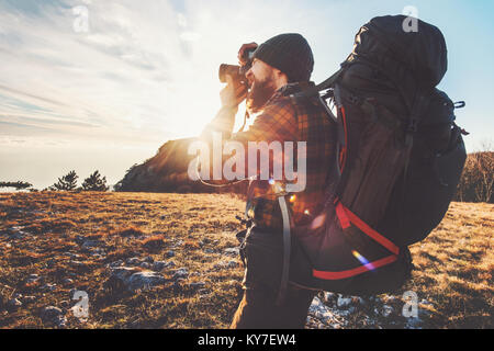 Man photographer with big backpack and camera taking photo of sunset mountains Travel Lifestyle hobby concept adventure active vacations outdoor Stock Photo