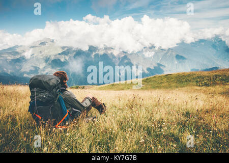Traveler with backpack relaxing sitting on grass valley at mountains landscape Travel Lifestyle hiking concept adventure summer wanderlust vacations o Stock Photo