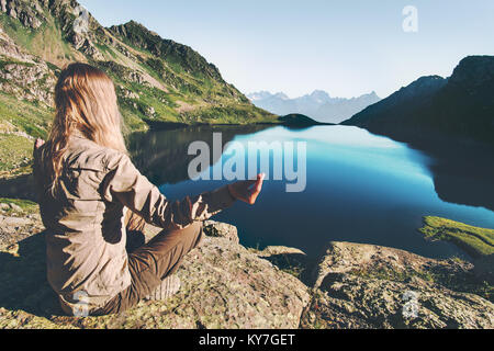 Woman meditating yoga at blue lake in mountains Travel Lifestyle relaxation emotional concept adventure summer vacations outdoor harmony with nature Stock Photo