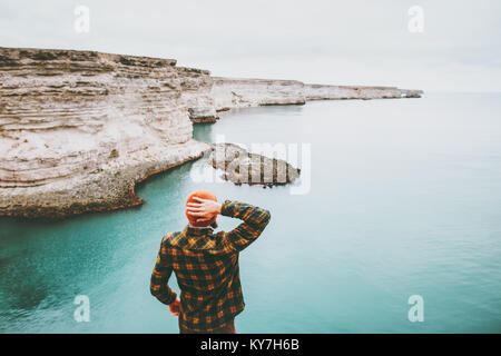 Man walking at cold sea Travel Fashion Lifestyle hat and cozy shirt clothing harmony with nature authentic style concept Stock Photo
