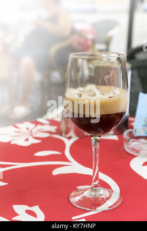 A glass of shakerato on a red tablecloth in an Italian open air cafe on a historic street. Stock Photo