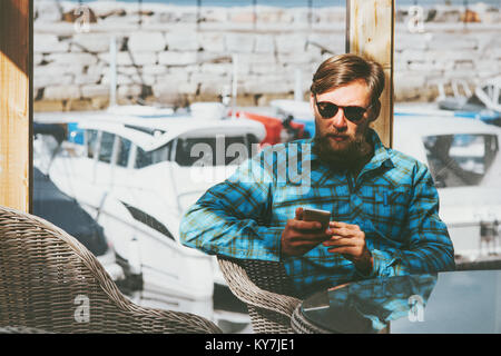 Bearded Man using smartphone Lifestyle success modern technology concept businessman sitting near window at the table Stock Photo
