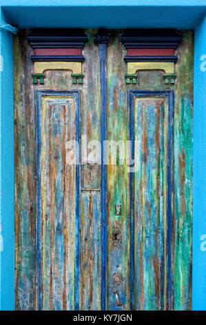 close up of an old wooden door with peeling paint in multiple colours. Stock Photo