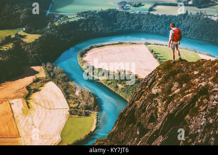 Travel Man on mountains cliff edge with backpack Adventure lifestyle concept active weekend summer vacations river aerial view Stock Photo