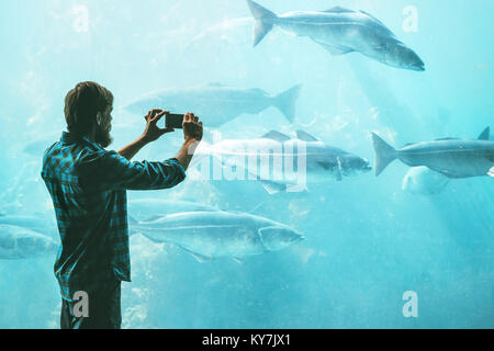 Man taking photo using smartphone of fish in big aquarium Travel Lifestyle concept modern technology Stock Photo