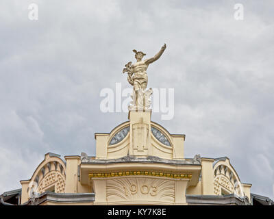 White stone statue of he Greek god Hermes holding a Caduceus staff and wearing winged helmet, on top of a renaissance revival building in Ljubljana, S Stock Photo