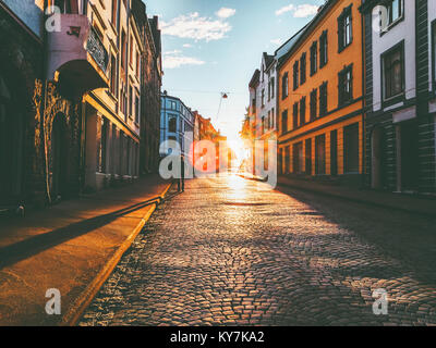 Man walking alone at sunset street Travel Lifestyle concept vacations cobblestone road city in Norway Stock Photo