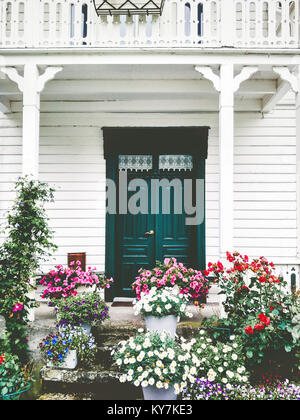 White wooden country house entrance door terrace cozy exterior with flowers design decoration and balcony retro style traditional building Stock Photo