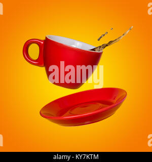 Creative surreal design with a red coffee cup and saucer on a yellow background. A cup and saucer flying in the air. Stock Photo