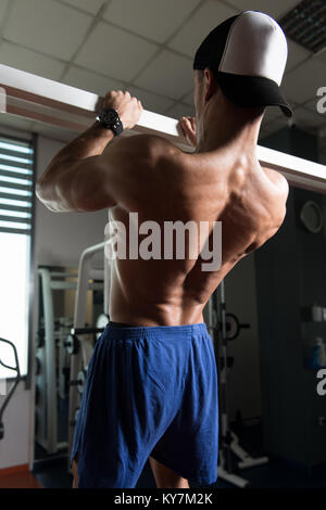 Man Athlete Doing Pull Ups - Chin-Ups In The Gym Stock Photo