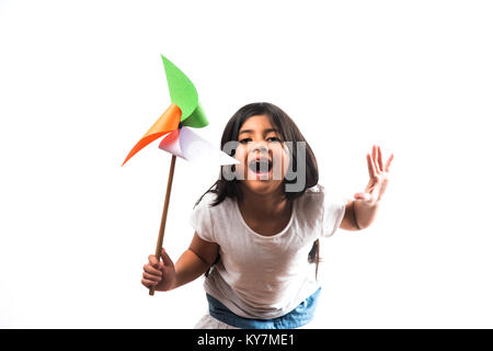 indian girl with paper windmill toy made up of tricolour or indian flag colours. Saluting, looking at camera or with red heart toy, celebrating 26 Jan Stock Photo