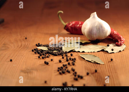 Bay leaves, head of garlic and peppercorns on wooden background Stock Photo