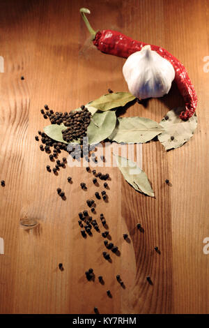 Bay leaves, head of garlic and peppercorns on wooden background Stock Photo