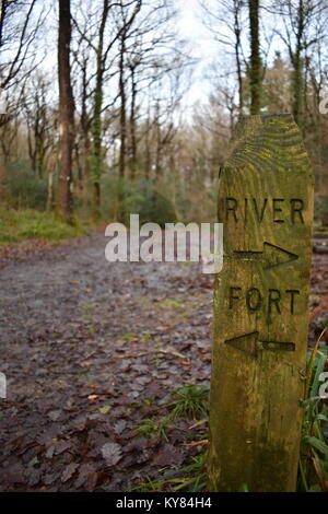 Wooden sign post indicating the directions to a river and a fort within a woodland footpath setting in Hembury Woods near Buckfast in Devon. Stock Photo