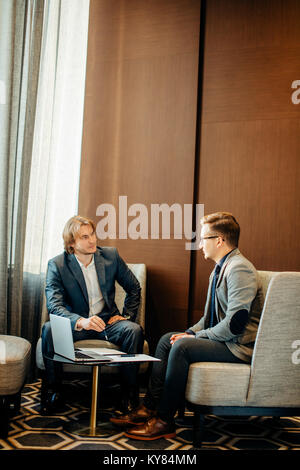 Two male employees consulting with laptop in cafe Stock Photo