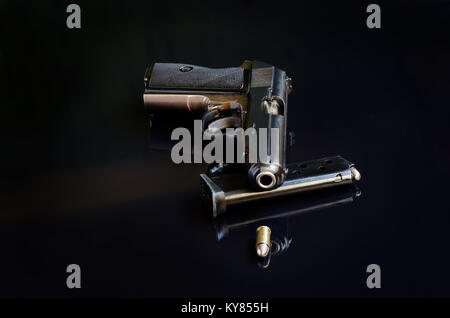 Handgun, charger and bullet on black reflective background Stock Photo