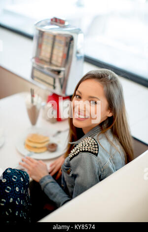 Pretty happy young woman sitting in the diner Stock Photo