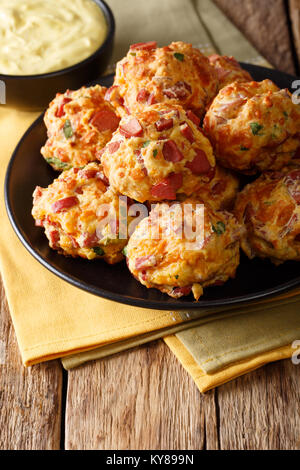 Freshly baked sausage balls with cheese cheddar on a plate and mustard sauce in a bowl close-up. vertical Stock Photo
