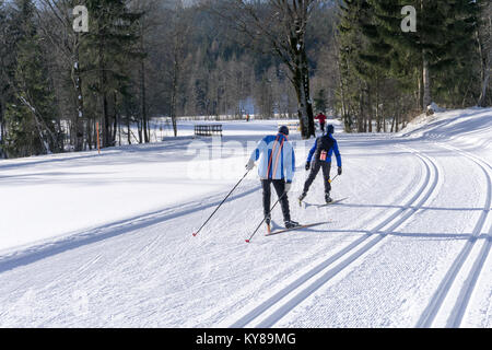 Groomed ski trails for cross country skiing with two cross-country skiers in winter sunny day in mountains Stock Photo