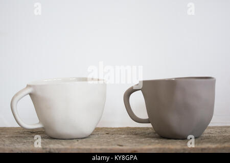 handmade, quirky ceramic cups, one bright, one dark, next to each other Stock Photo
