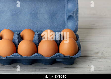 Chicken eggs in a blue package on a gray wooden background. Selective focus. Stock Photo