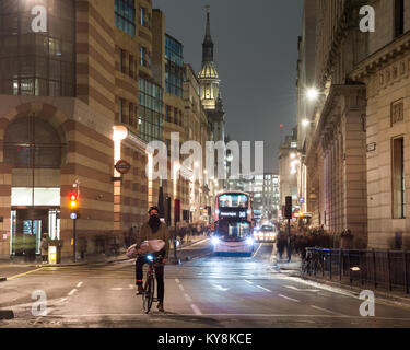 London, England, UK - January 11, 2018: Pedestrians walk past cyclists and buses waiting at Bank Junction in the City of London, between old churches  Stock Photo