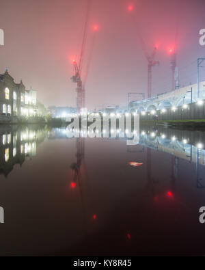London, England, UK - December 30, 2016: Warehouses, tower cranes and the North London Line railway are reflected in the Regent's Canal between Kentis