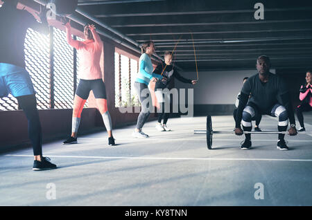 Group of active young multiracial friends doing a variety of crossfit exercises inside a commercial parking area in a concept of an active healthy urb Stock Photo