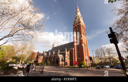 London, England, UK - April 12, 2011: Sun shines on the red brick Victorian Gothic tower and spire of St John the Divine parish church in Kennington,  Stock Photo