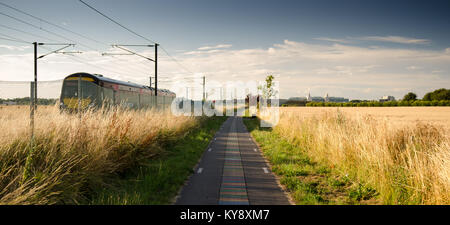 Cambridge, England, UK - In farmland south of Cambridge, a Greater Anglia Class 170 regional diesel passenger train passes the 'DNA way' cycle path, p Stock Photo