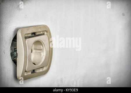 Old European electrical socket outlet falling out of wall and in need of repair. Outlet on old dirty wall Stock Photo