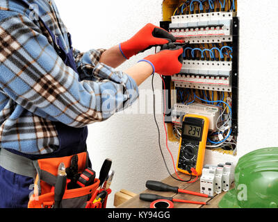 Young electrician technician measures with a multimeter the voltage in a electrical panel Stock Photo
