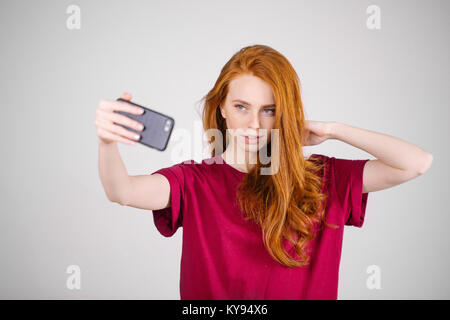 redhead girl takes a selfie. She has long red hair. wears marsala t-shirt Stock Photo